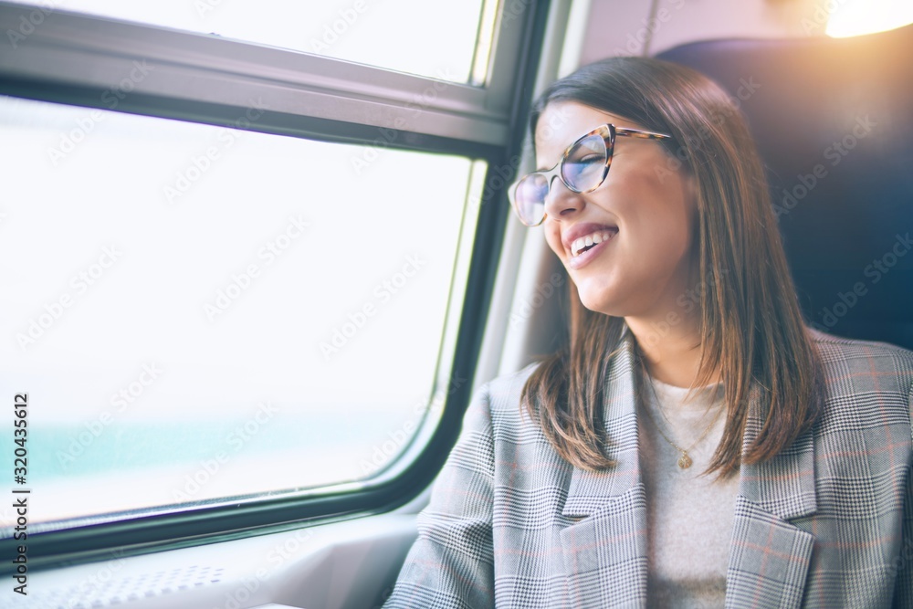 Young beautiful woman smiling happy and confident. Sitting with smile on face travelling by train Young beautiful woman smiling happy and confident. Sitting with smile on face travelling by train