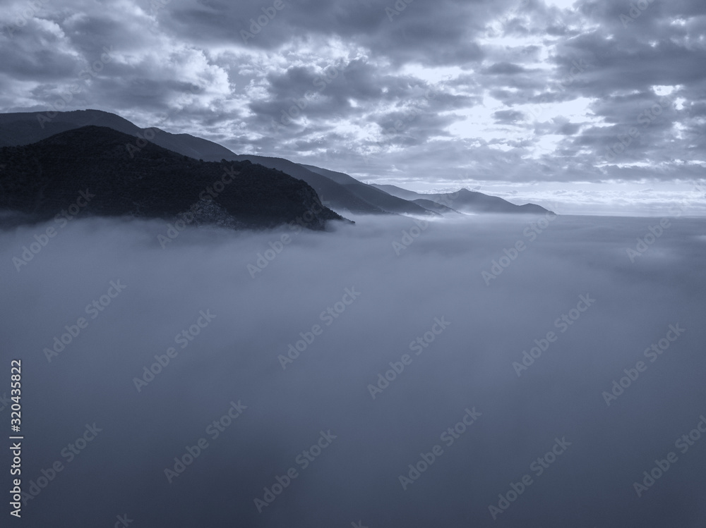 Aerial view of a mountain in the fog at sunrise, Tuscany, Italy.