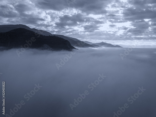 Aerial view of a mountain in the fog at sunrise, Tuscany, Italy.