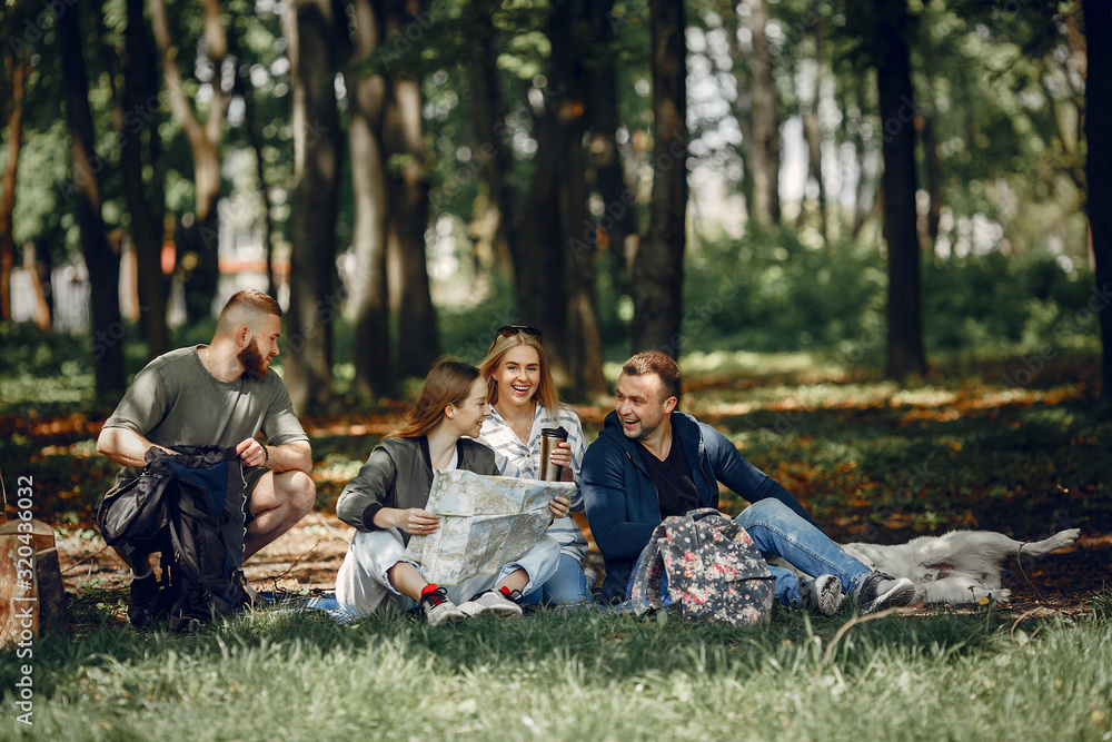 Tourists in a summer forest. Friends with a map. Tourists in a summer forest. Friends with a map.