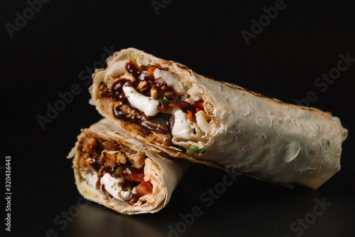 Shawarma sandwich gyros fresh roll of lavash pita bread chicken beef shawarma falafel RecipeTin Eatsfilled with grilled meat, mushrooms, cheese. Traditional Middle Eastern snack. On black background photo