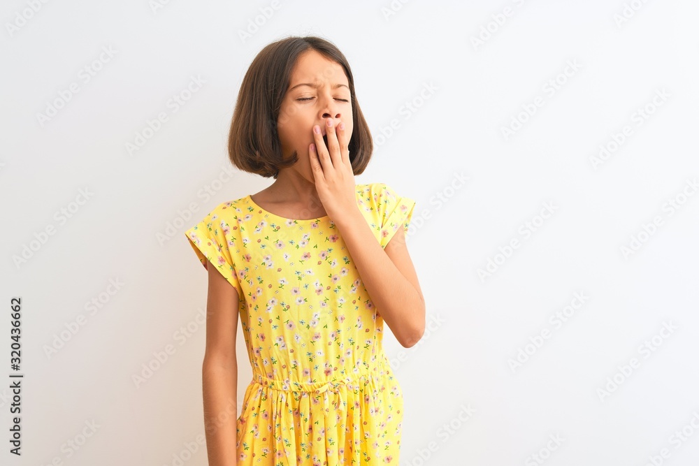 Young beautiful child girl wearing yellow floral dress standing over isolated white background bored yawning tired covering mouth with hand. Restless and sleepiness. Young beautiful child girl wearing yellow floral dress standing over isolated white background bored yawning tired covering mouth with hand. Restless and sleepiness.