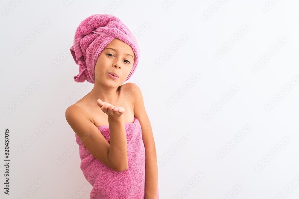 Beautiful child girl wearing shower towel after bath standing over isolated white background looking at the camera blowing a kiss with hand on air being lovely and sexy. Love expression. Beautiful child girl wearing shower towel after bath standing over isolated white background looking at the camera blowing a kiss with hand on air being lovely and sexy. Love expression.