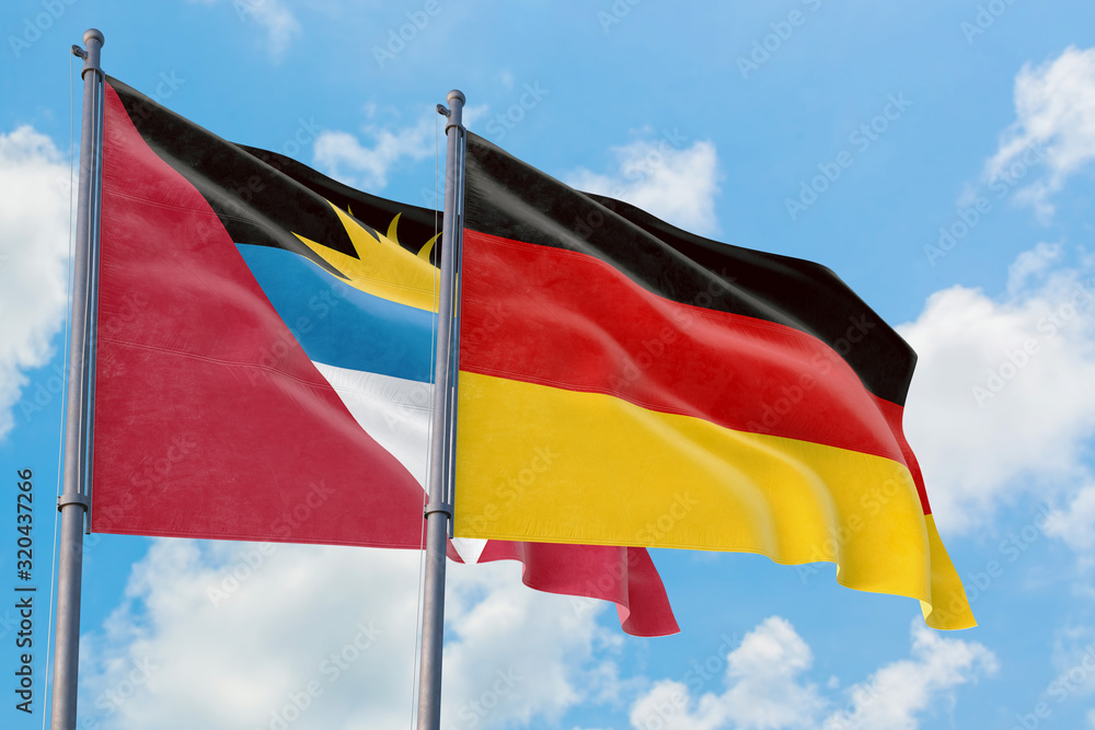 Germany and Antigua and Barbuda flags waving in the wind against white cloudy blue sky together. Diplomacy concept, international relations. Germany and Antigua and Barbuda flags waving in the wind against white cloudy blue sky together. Diplomacy concept, international relations.