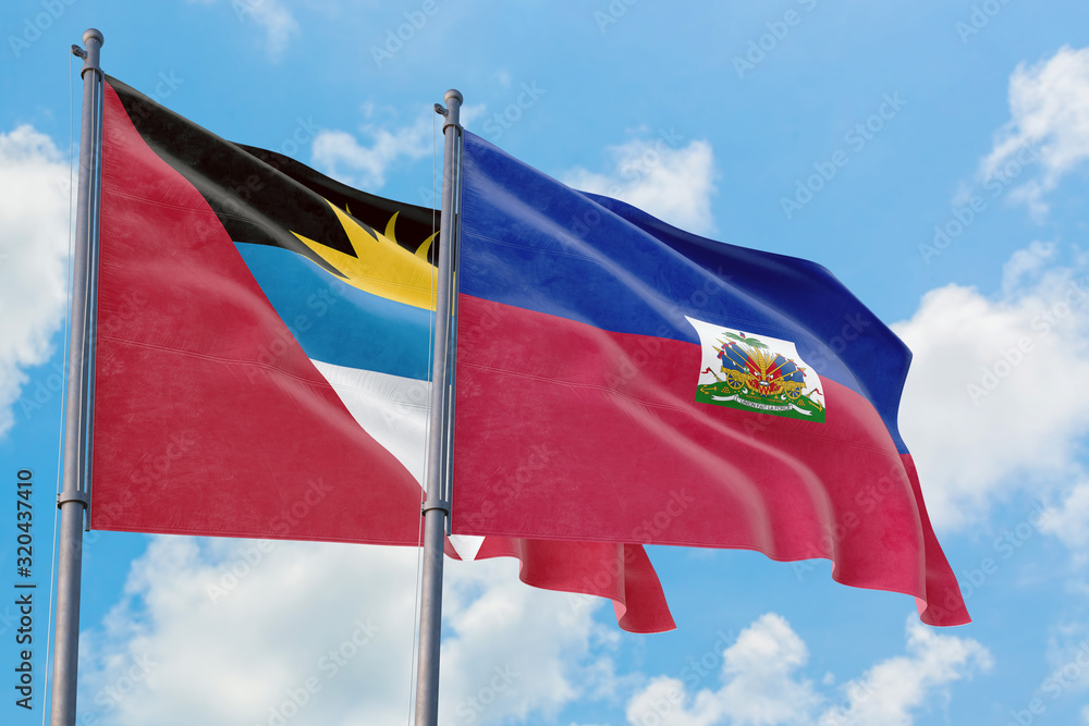 Haiti and Antigua and Barbuda flags waving in the wind against white cloudy blue sky together. Diplomacy concept, international relations. Haiti and Antigua and Barbuda flags waving in the wind against white cloudy blue sky together. Diplomacy concept, international relations.