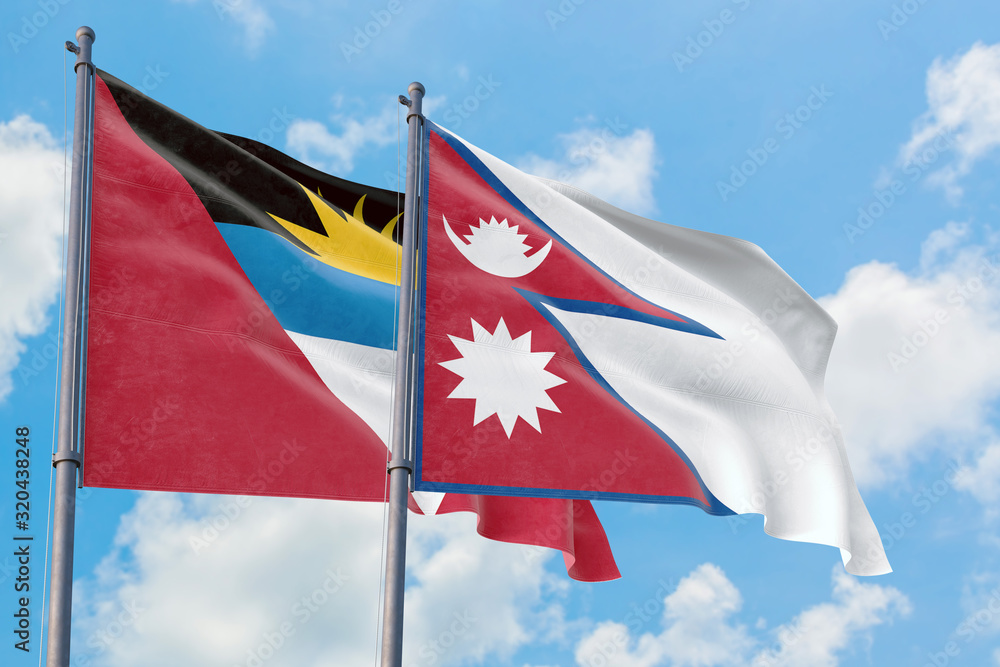 Nepal and Antigua and Barbuda flags waving in the wind against white cloudy blue sky together. Diplomacy concept, international relations. Nepal and Antigua and Barbuda flags waving in the wind against white cloudy blue sky together. Diplomacy concept, international relations.