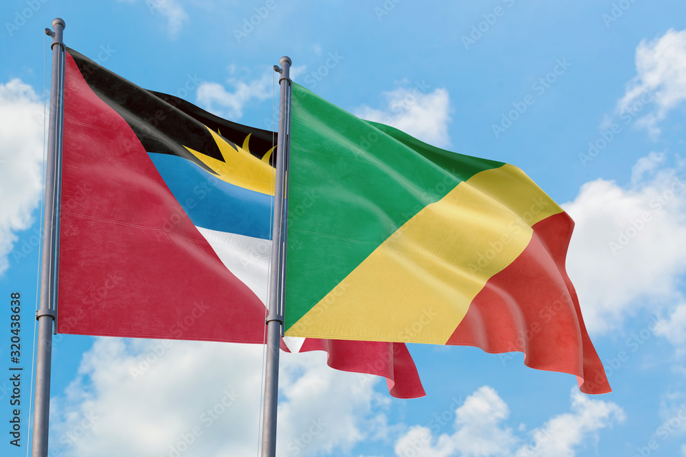 Republic Of The Congo and Antigua and Barbuda flags waving in the wind against white cloudy blue sky together. Diplomacy concept, international relations. Republic Of The Congo and Antigua and Barbuda flags waving in the wind against white cloudy blue sky together. Diplomacy concept, international relations.