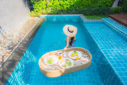 Portrait young asian woman happy smile enjoy with floating breakfast tray in swimming pool in hotel © siraphol