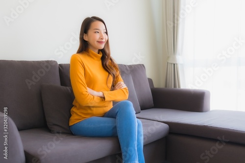 Portrait young asian woman happy relax smile on sofa chair with pillow in living room