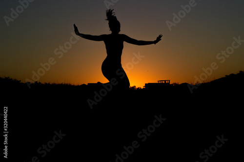 silhouette of young woman jumping in sunset