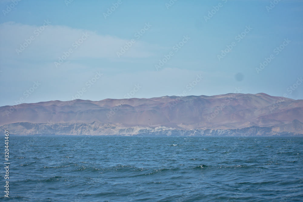 Ocean landscape with a sandy mountain in the background in Paracas Peru