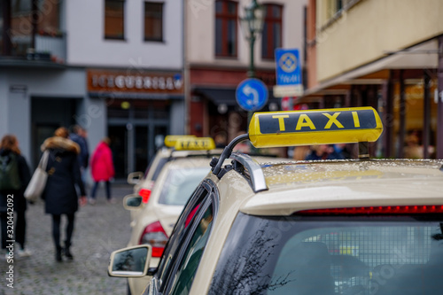 Selected focus at Taxi sign on roof of Taxi yellow cabs park at Carlsplatz in old town Düsseldorf, Germany. Queue of yellow taxis in europe.