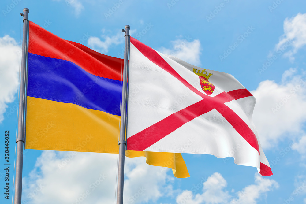 Jersey and Armenia flags waving in the wind against white cloudy blue sky together. Diplomacy concept, international relations. Jersey and Armenia flags waving in the wind against white cloudy blue sky together. Diplomacy concept, international relations.