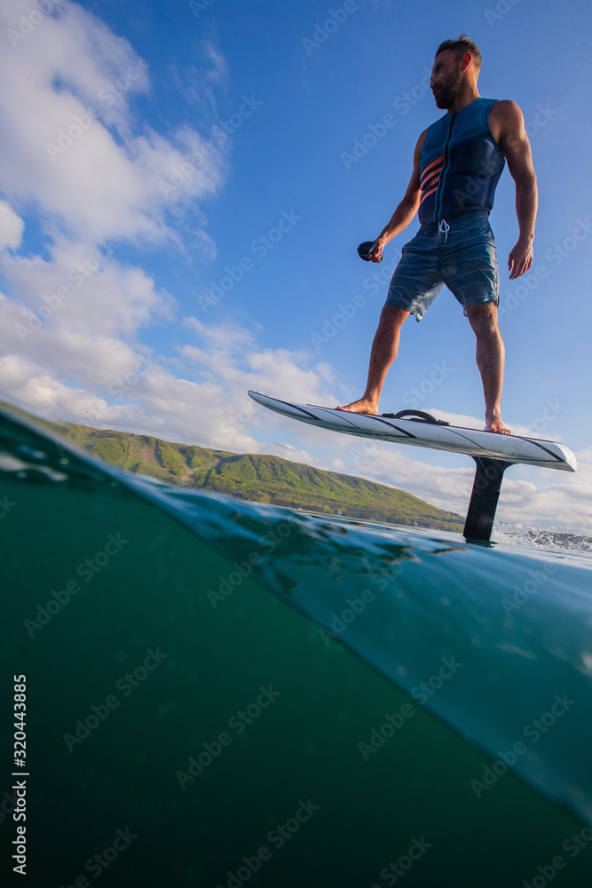 Man riding an electric hydrofoil foil board on a lake with a life jacket