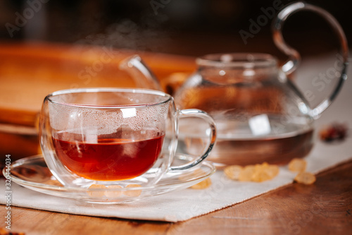 Cup of hot tea with rock sugar, dry leaves served in thermo glass cup