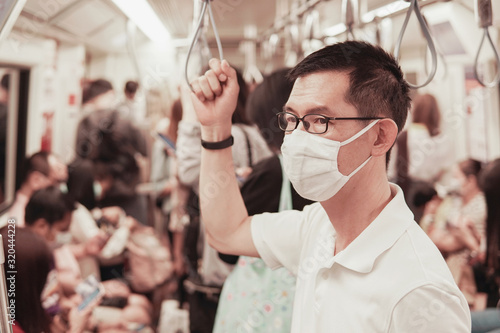 Middle aged Asian man wearing glasses and medical face mask on public train,  coronavirus,  covid delta virus post pandemic, air pollution and health, new normal, reopening, stop asian hate concept