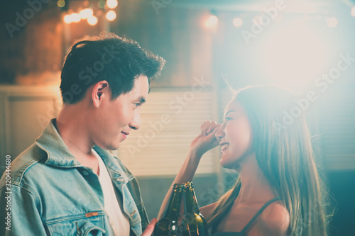 Couples dancing,Young Asian people sweetheart philander dancing and drinking in evening party inside a night club hand holding beer bottle with light flare effect