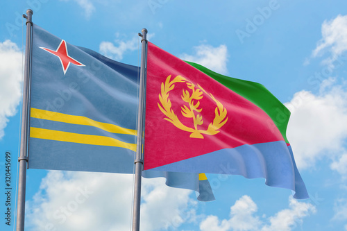 Eritrea and Aruba flags waving in the wind against white cloudy blue sky together. Diplomacy concept, international relations.