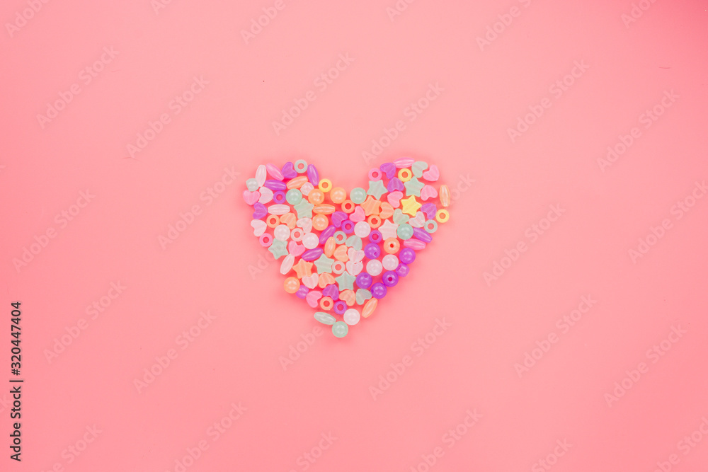 The heart shapes of colorful pony and star bead over the pink pastel background. Greeting cards, Love and Valentines day concept. Flat lay, top view, copy space.