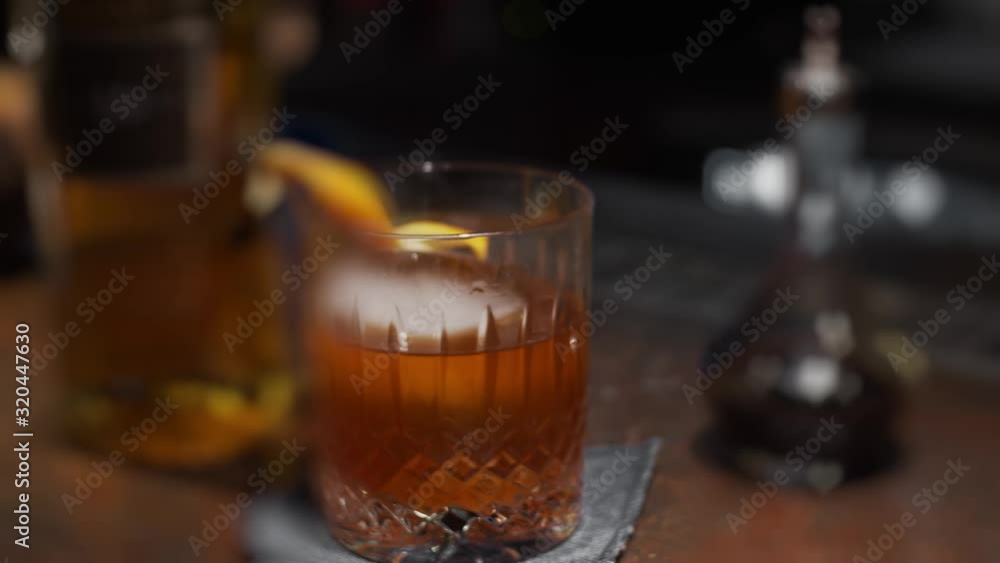 Glass with orange peel and ice cocktail, slow motion, shallow depth of field. Focus transition Glass with orange peel and ice cocktail, slow motion, shallow depth of field. Focus transition