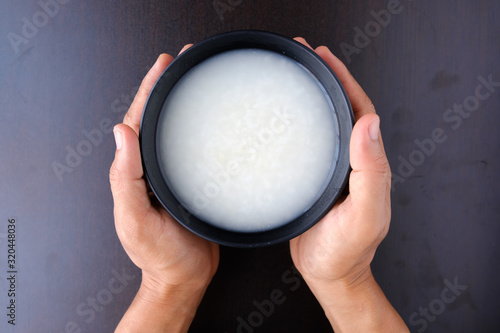 Hand holding bowl of mush rice