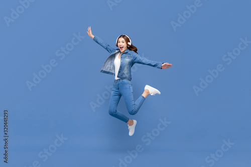 Asian woman jumping while listening to music on headphones