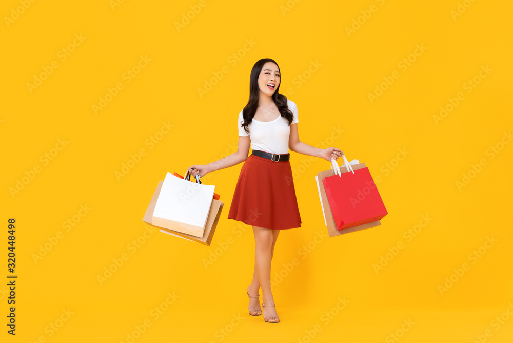 Young beautiful Asian woman holding colorful shopping bags