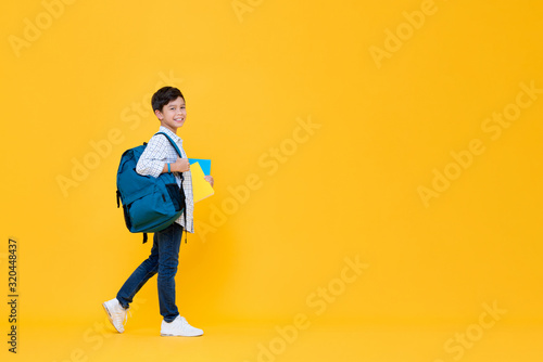 Handsome 10 year-old schoolboy holding books and backpack
