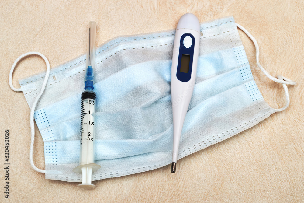 Syringe, thermometer, and mask are on the tiled table in the hospital. Disease prevention. Treatment and prevention. Virus and epidemic Syringe, thermometer, and mask are on the tiled table in the hospital. Disease prevention. Treatment and prevention. Virus and epidemic