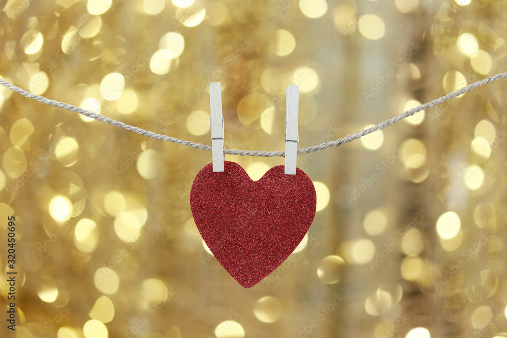 Red heart hanging on a hemp rope on the gold bokeh background. Red heart hanging on a hemp rope on the gold bokeh background.