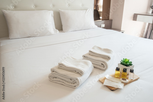 Set of hotel amenities (such as towels, shampoo, soap etc) on the bed. Hotel amenities is something of a premium nature provided in addition to the room when renting a room. photo