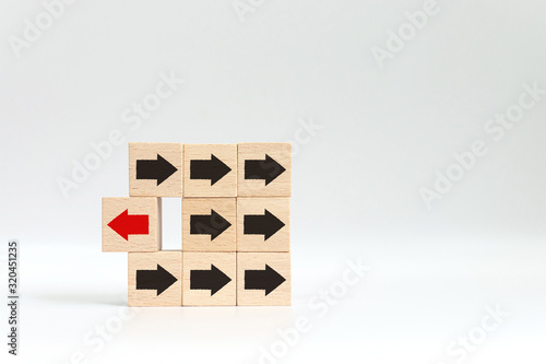 Wooden block with red arrow facing the opposite direction black arrows, Unique, think different, individual and standing out from the crowd concept. photo