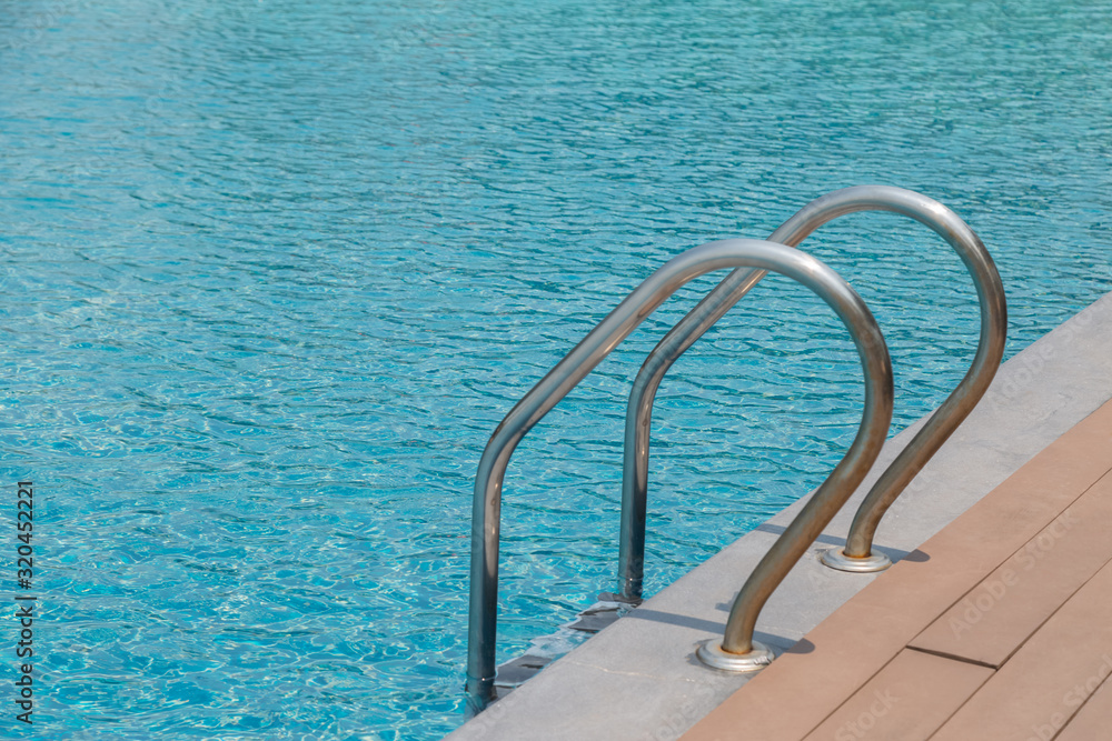 Stairs Ladder and handle down the swimming pool with blue water Stairs Ladder and handle down the swimming pool with blue water