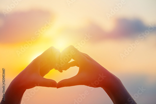 Hands make in heart form love with silhouette at sun set