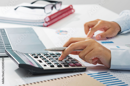 businesswoman working on desk using calculator analyzing finance accounting in office