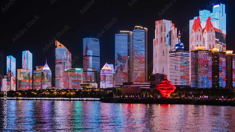 Fototapeta Scenic night view from the Urban park new town seaside of Qingdao, China.Seaside tourist town that is popular with Chinese people.Building lighting show With beautiful color lights at night.