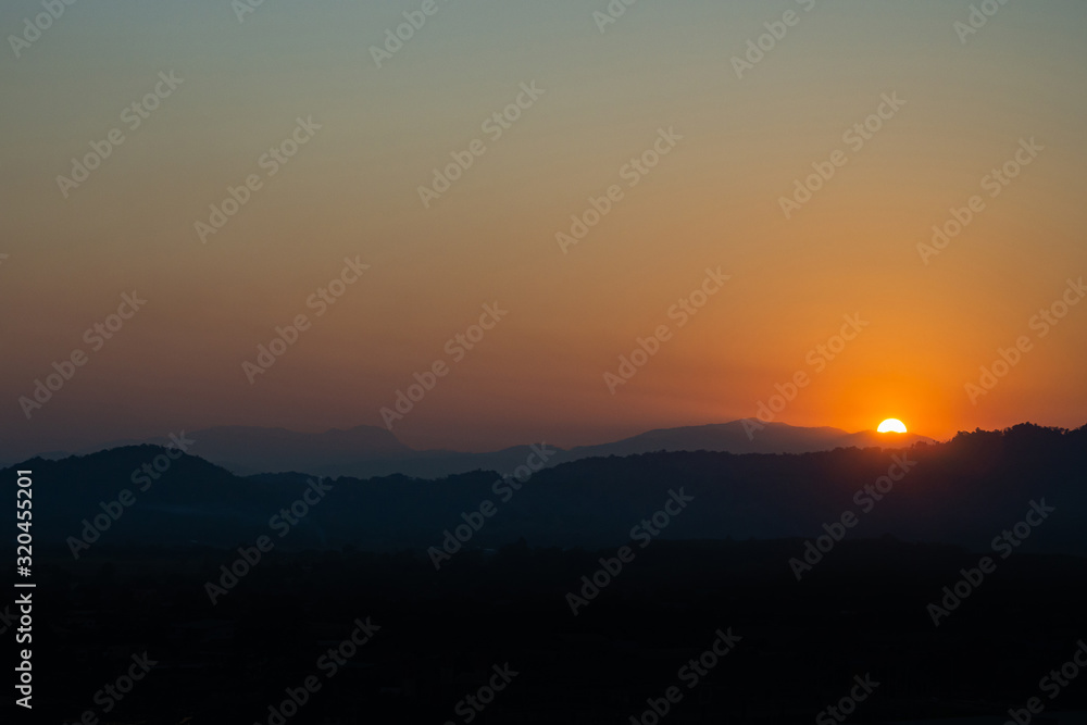 Beautiful dramatic of sunset in the mountains. Landscape with sunlight shining through orange. Nature concept