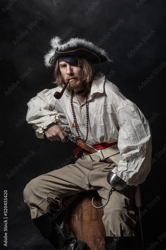 medieval bearded pirate with a sword and gun. concept photo of handsome man in a pirate vintage costume with pistol and saber medieval bearded pirate with a sword and gun. concept photo of handsome man in a pirate vintage costume with pistol and saber