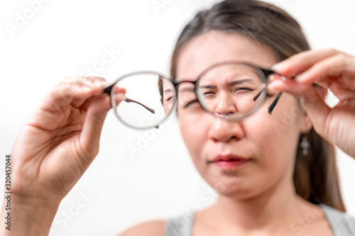 Asian woman holding glasses on white background, Selective focus on glasses , myopia and eyesight problem concept.