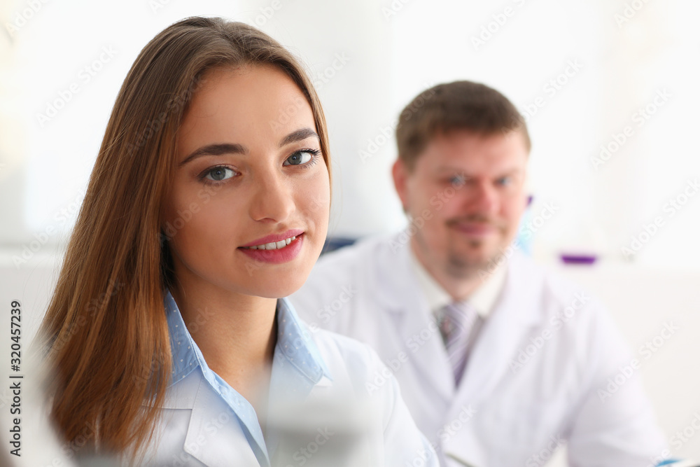 Smiling beautiful technician woman portrait and sample bottle with poison fluid. Medical worker in uniform use reagent tube for virus infection exam or biological toxic reaction drug creation Smiling beautiful technician woman portrait and sample bottle with poison fluid. Medical worker in uniform use reagent tube for virus infection exam or biological toxic reaction drug creation