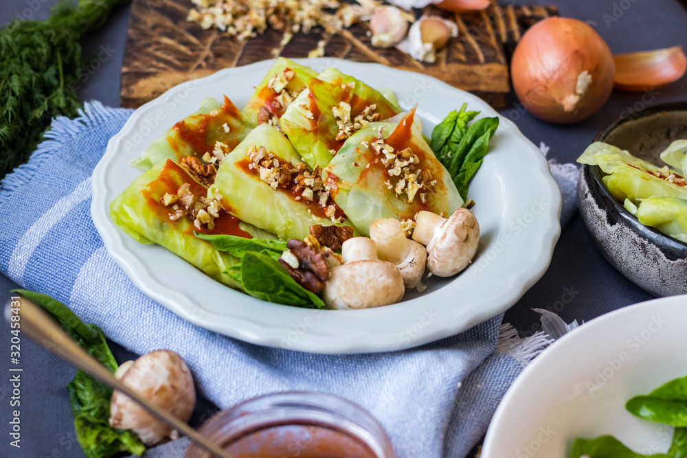 Cabbage rolls with mushrooms and tomato paste sauce walnuts topping. Healthy dietary vegan food. Woman holds cabbage rolls Cabbage rolls with mushrooms and tomato paste sauce walnuts topping. Healthy dietary vegan food. Woman holds cabbage rolls
