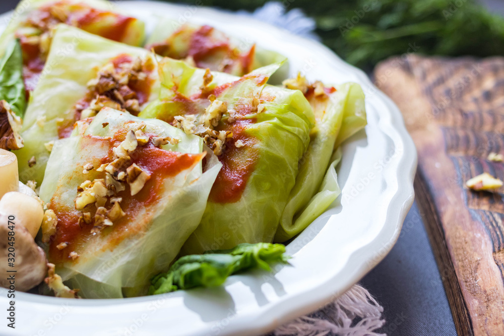 Cabbage rolls with mushrooms and tomato paste sauce walnuts topping. Healthy dietary vegan food. Woman holds cabbage rolls