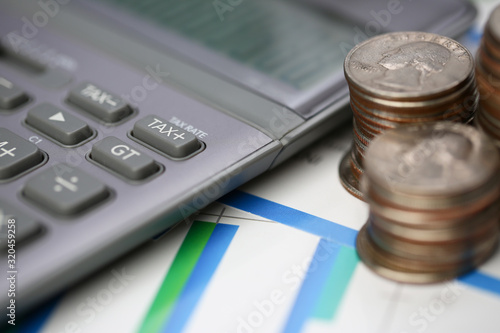 Silver calculator with gray keyboard is lying on desk cash quarter plots in home office setting. Calculation of family expenses social income population freelance irs situation growth research concept photo