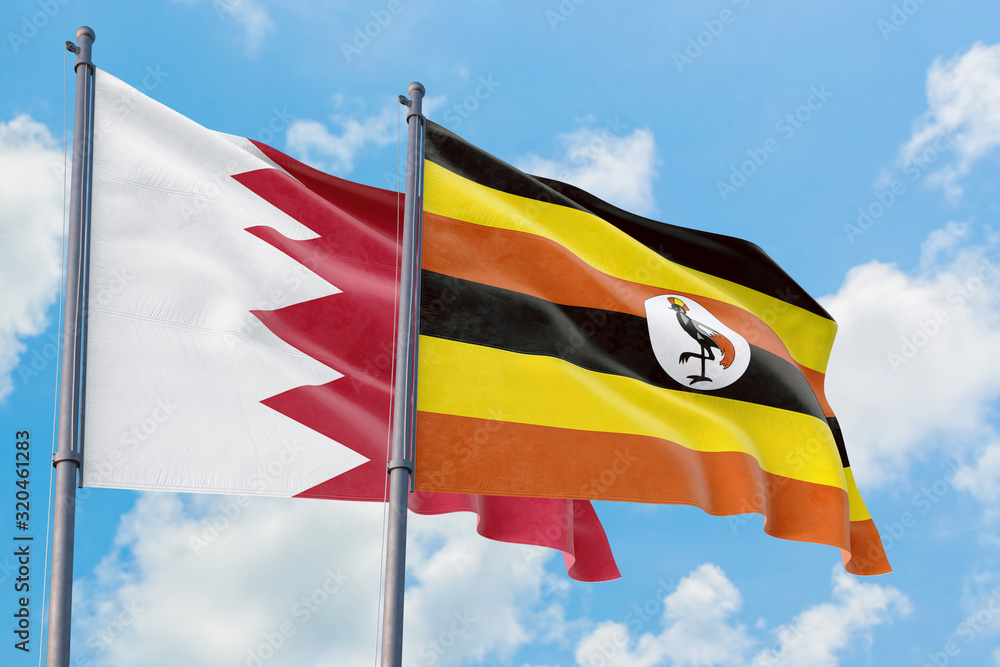 Uganda and Bahrain flags waving in the wind against white cloudy blue sky together. Diplomacy concept, international relations. Uganda and Bahrain flags waving in the wind against white cloudy blue sky together. Diplomacy concept, international relations.