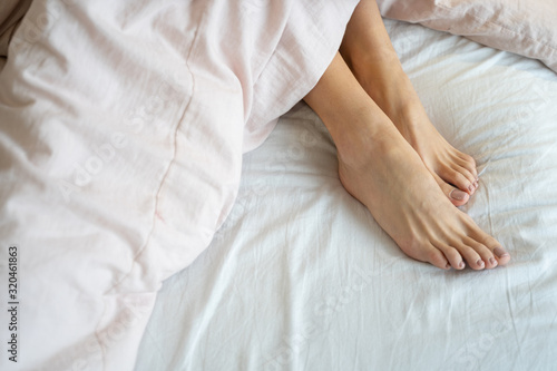 Woman with bare feet relaxing in bed