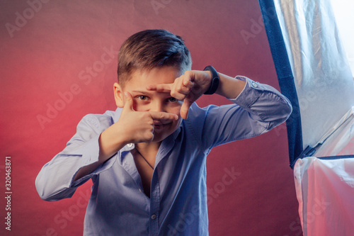 The boy is dark in a blue shirt on a purple and maroon background.