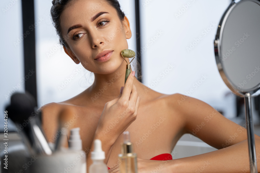 Obraz na płótnie Lovely calm female holding a face massager w salonie