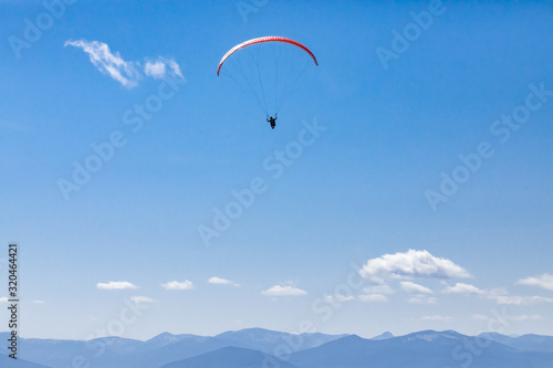 Beautiful scene of flying paraglider over Kootenay valley mountains. Long shot of flying paraglider man. Recreational and competitive adventure sport