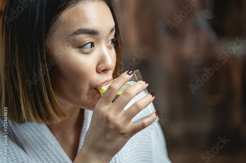 Calm Asian lady drinking tea in beauty salon