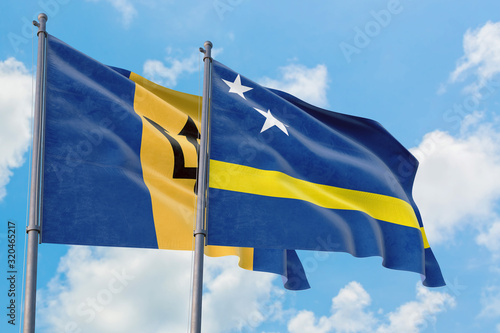 Curacao and Barbados flags waving in the wind against white cloudy blue sky together. Diplomacy concept, international relations.
